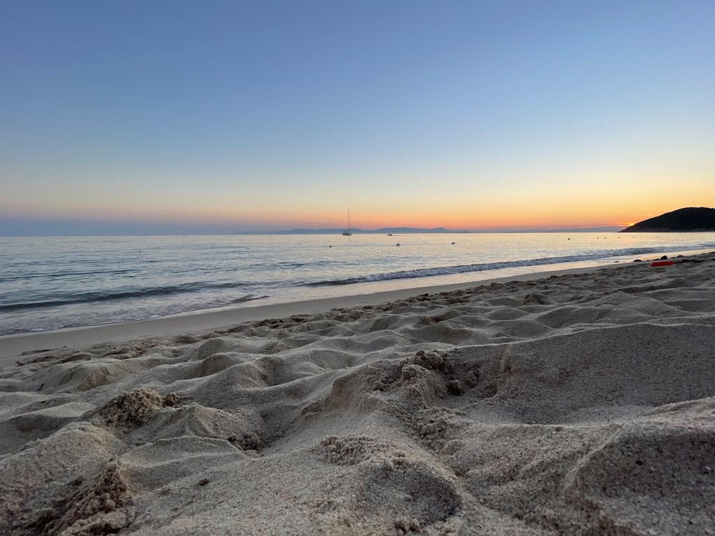 Serene beach view at sunset with sandy shores and calm sea, perfect for relaxation.